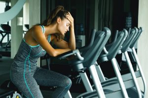 Woman in the gym with overtraining symptoms