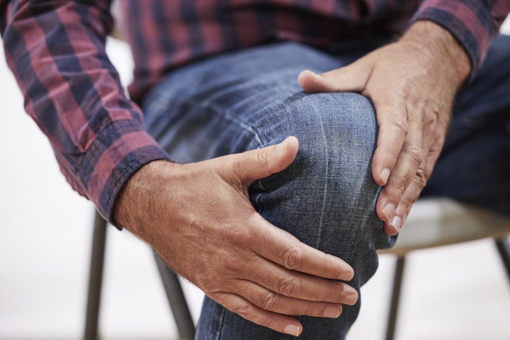 Close Up Of Mature Man Suffering From Pain Or Arthritis Clutching Knee