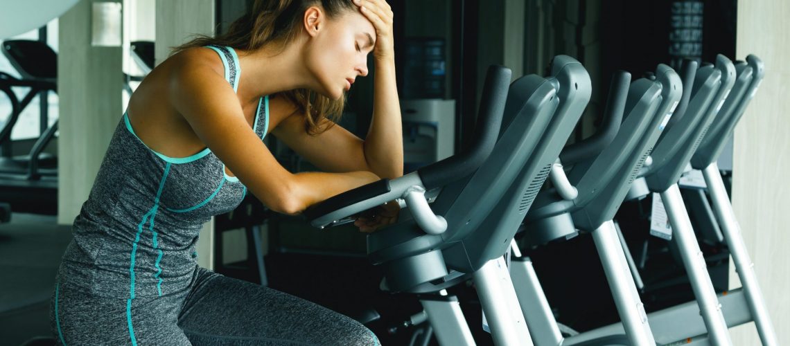 Woman in the gym with overtraining symptoms